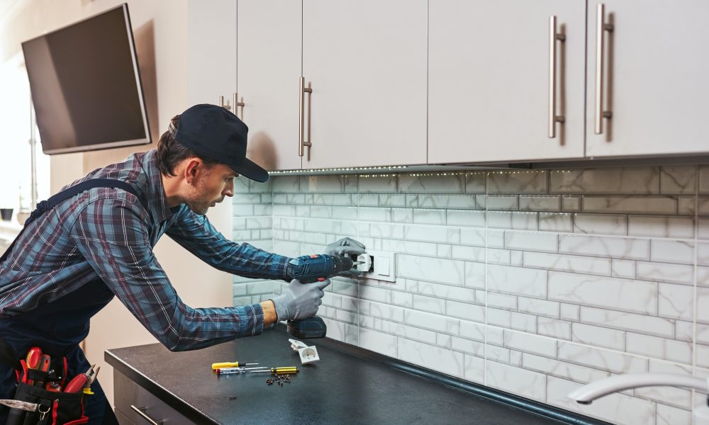 Electricity protection. Side view of young handyman with perforator