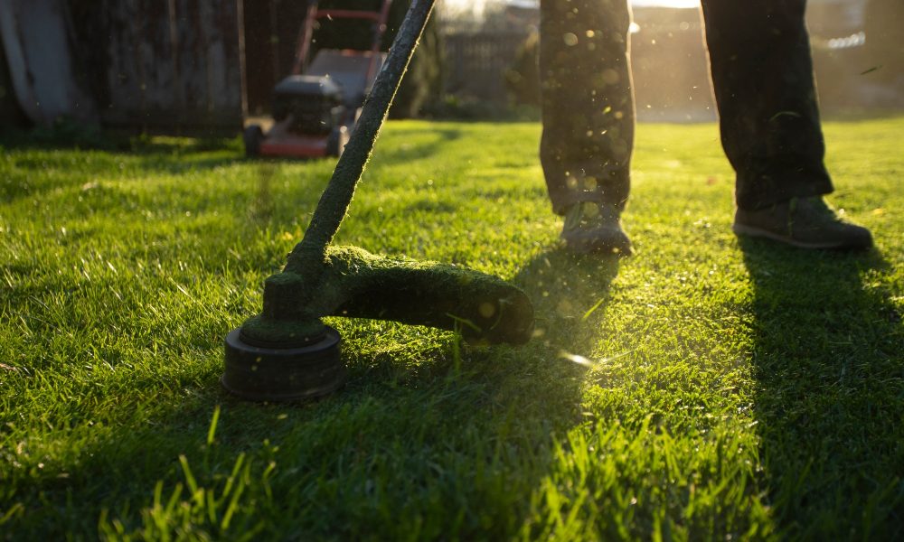 Garden worker with lawn mover. Garden works in spring.