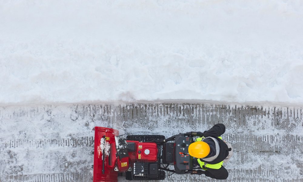 Worker cleaning snow on the sidewalk with a snowblower. Wintertime
